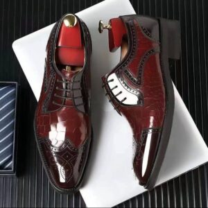 Sunt pantofi eleganți, cel mai probabil de tip dress shoes (pantofi de gală/ocazie/afaceri), cu model Brogue (prezintă perforații decorative, vizibile în special pe vârf și pe marginile cusăturilor). Stilul cusăturilor pe părțile laterale sugerează o variantă de Wingtip sau Longwing.