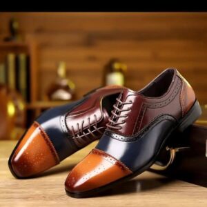 Pantofi de costum/ocazie, de tip dress shoes, probabil Oxford sau Derby cu șireturi.
​Culoare și Design: Pantofii sunt bi-tonali sau multi-tonali, cu un design distinctiv de tip cap-toe sau wingtip (parțial).