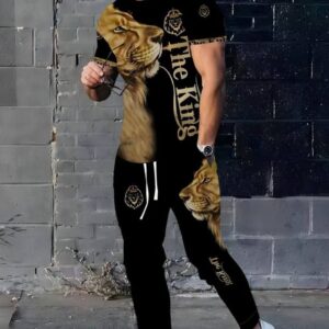 Tricou cu mânecă scurtă: De culoare predominant neagră, cu un design mare, vibrant, ce include un cap de leu în nuanțe de auriu/maro pe piept și textul "The King" scris vertical cu litere aurii. Mânecile par să aibă și un model de camuflaj sau pete de animal (leopard/ghepar), iar pe guler sau piept apare și o emblemă/siglă cu un leu sau o coroană.